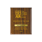 A photo of a Walnut Piano Finish plaque with a laser engrave text and graphics, and a traditional engraved name plate.