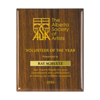 A photo of a Walnut Piano Finish plaque with a laser engrave text and graphics, and a traditional engraved name plate.